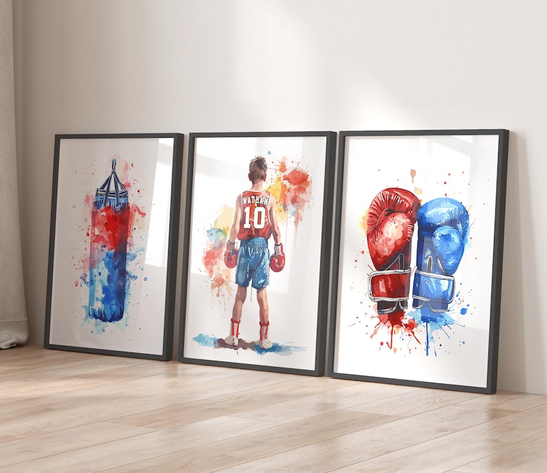 May include: Three watercolor paintings on canvas with black frames. The first painting shows a red and blue boxing bag with watercolors splattered around it. The second painting shows a young boxer wearing red shorts and a red and white jersey with the number 10 on it. The third painting shows a pair of boxing gloves, one red and one blue, with watercolors splattered around them.