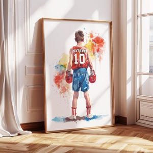 May include: A watercolor painting of a young boxer wearing red boxing gloves and a red and white jersey with the name "Nathan" and the number "10" on the back. The boxer is standing in a fighting stance with a colorful watercolor background.