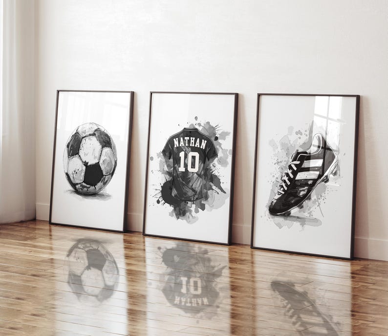 May include: Three framed black and white watercolor prints featuring soccer-themed art. The prints depict a soccer ball, a jersey with the name "Nathan" and the number 10, and a soccer cleat.