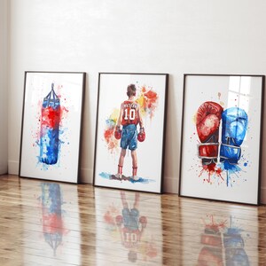 May include: Three watercolor paintings on canvas with a boxing theme. The first painting shows a red and blue boxing bag with watercolors splattered around it. The second painting shows a boxer wearing red shorts and a blue and red jersey with the number 10 on it. The third painting shows a pair of red and blue boxing gloves with watercolors splattered around them.