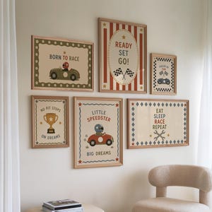 May include: A gallery wall set of six framed prints featuring racing-themed illustrations in red, blue, and green. The prints include text such as BORN TO RACE, READY SET GO!, FUELED BY FUN, NO PIT STOPS ON DREAMS, LITTLE SPEEDSTER BIG DREAMS, and EAT SLEEP RACE REPEAT.