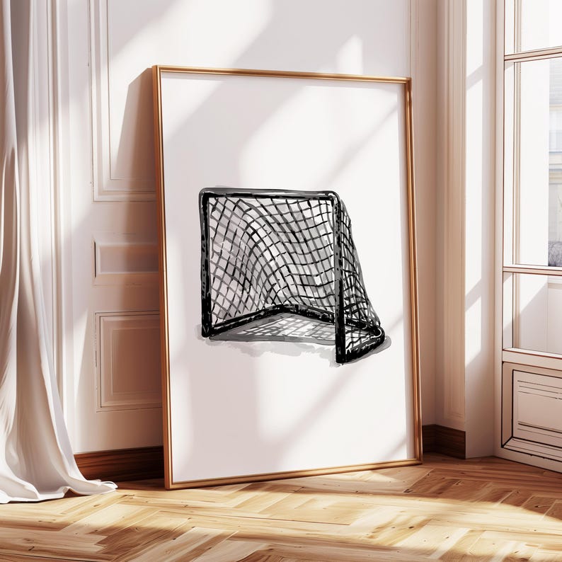 May include: A framed print featuring a black and white watercolor illustration of a hockey goal. The goal net is detailed with a grid pattern, and the artwork is set against a white background. The frame is gold.