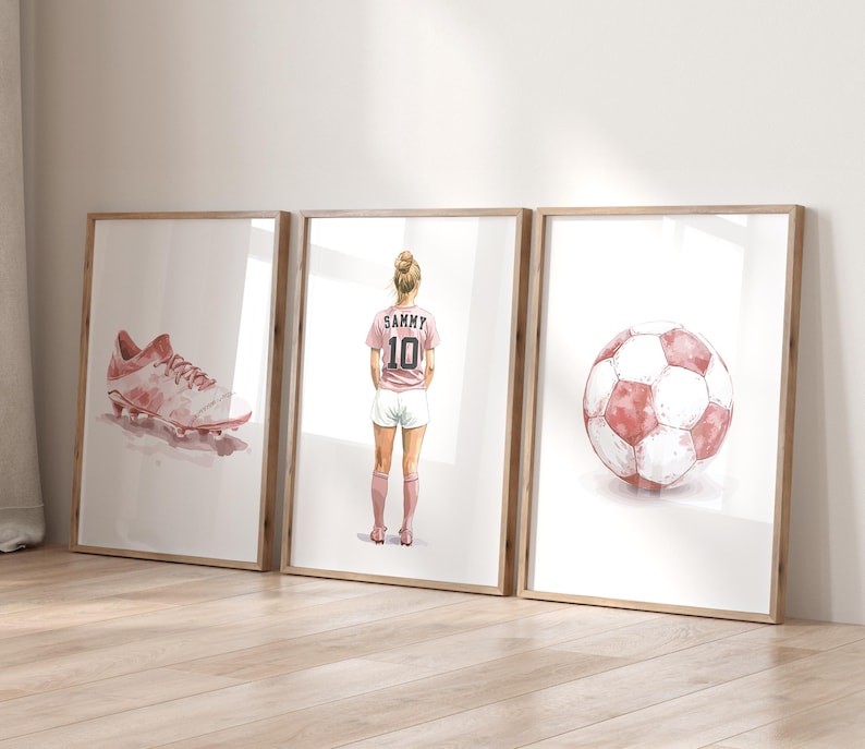 May include: Three watercolor illustrations in frames. The first shows a pink soccer cleat. The second shows a female soccer player wearing a pink jersey with the name "Sammy" and the number "10" on the back. The third shows a pink and white soccer ball.