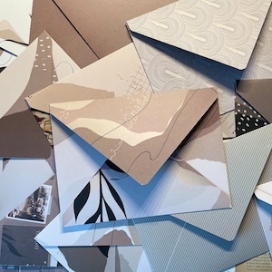 May include: A stack of patterned envelopes in various shades of brown and grey. The envelopes feature abstract designs, including geometric shapes, lines, and organic patterns.