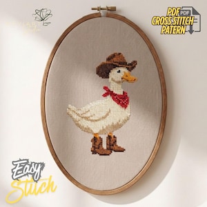 K&ouml;nnte beinhalten: Kreuzstichmuster einer wei&szlig;en Ente mit braunem Cowboyhut, rotem Halstuch und braunen Stiefeln. Die Ente ist auf beigem Stoff gestickt, umrahmt von einem h&ouml;lzernen Stickrahmen. Der Text auf dem Bild lautet "PDF Cross Stitch Pattern" und "Easy Stitch".