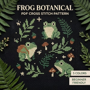 May include: A cross stitch pattern on black fabric featuring three green frogs, brown mushrooms, and green fern leaves. The text reads FROG BOTANICAL PDF CROSS STITCH PATTERN, 5 COLORS, and BEGINNER FRIENDLY. The design uses small stitches to create images.
