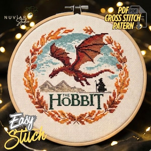 May include: Cross-stitch pattern featuring a red dragon soaring over a mountain range, with the text "The Hobbit" below. The design is framed by a circular border of autumn leaves, with the words "Easy Stitch" and "PDF Cross Stitch Pattern" also visible.