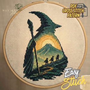 May include: Cross-stitch design in a wooden hoop, depicting a wizard silhouette with a mountain and sunset. The colour scheme includes green, yellow, and blue. The image includes the text "PDF Cross Stitch Pattern" and "Easy Stitch".
