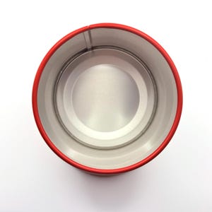 May include: A top-down view of an empty cylindrical metal tin with a bright red exterior rim and a smooth, unpainted silver-toned interior. The container features a circular base and vertical walls, showcasing a clean, industrial design.