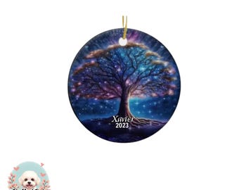 May include: A round ceramic ornament featuring a vibrant cosmic tree illustration with blue, purple, and gold hues against a starry night sky. The name Xavier and the year 2023 are printed in white text at the base of the tree trunk.