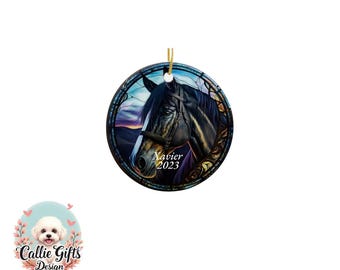 May include: A round ceramic ornament featuring a detailed illustration of a black horse with a bridle against a stained-glass style background. The text Xavier 2023 is printed in white on the lower portion of the horse. A gold string is attached.