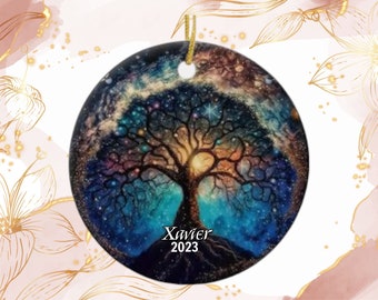 May include: A round ceramic ornament featuring a vibrant tree design against a starry night sky. The tree's branches reach upwards, and the ornament has the name "Xavier" and the year "2023" printed on it. A gold string is attached for hanging.