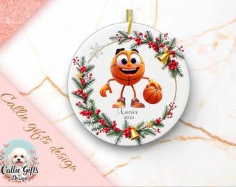May include: A round ceramic ornament featuring a basketball-themed emoji character holding a basketball. The ornament is decorated with a wreath of greenery, red berries, and gold bells. The name "Xavier" and the year "2023" are printed on the ornament.