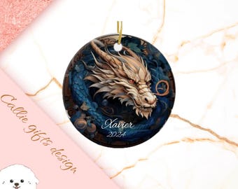 May include: A round, white ceramic ornament with a blue and gold dragon design. The dragon is curled around a blue orb and has a white and gold face. The ornament has the name "Xavier" and the year "2024" written on it.