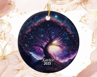 May include: Round ceramic ornament featuring a vibrant tree illustration with a purple and blue color scheme. The tree is set against a starry night sky with the name "Xavier" and the year "2023" printed on the bottom. A gold string is attached for hanging.