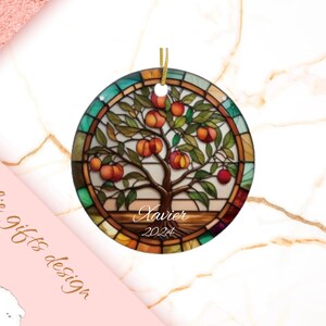 May include: A round, stained glass ornament with a tree and fruit design. The ornament is decorated with a colorful stained glass pattern and features the name "Xavier" and the year "2024".
