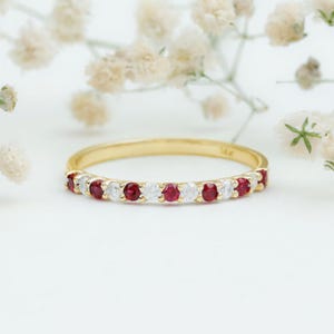 Könnte beinhalten: Ein zarter Goldring mit abwechselnd roten Rubinen und weißen Diamanten.