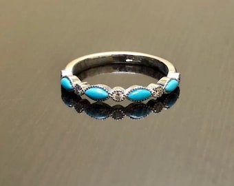 May include: A silver band ring with turquoise and clear stones set in a delicate design.