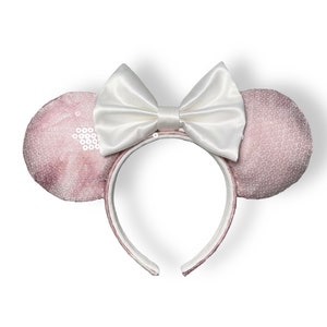 May include: Pink sequined mouse ears headband with a white satin bow.