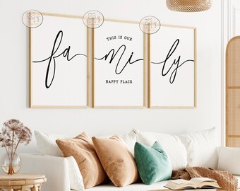 May include: Three framed prints with the words "This is our family happy place" in black script font on a white background. The prints are hanging on a white wall above a white couch with brown and green throw pillows.