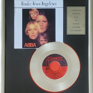 Könnte beinhalten: Gerahmte, platinbeschichtete Schallplatte des ABBA-Albums "Voulez-Vous/Angeleyes". Der Rahmen enthält das Albumcover und eine Plakette mit der Aufschrift "This Special Edition Platinum Plated Record Is In Recognition Of Outstanding Artistic Achievement."
