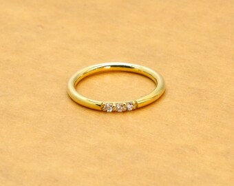 May include: A simple gold band ring with three small diamonds set in a row.