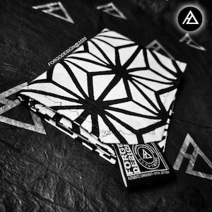 May include: A black and white geometric patterned wallet with a black leather tag that says "FORGODESIGN@2020" and has a triangle logo.