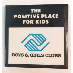 May include: A square pinback button featuring a black top section with the white text THE POSITIVE PLACE FOR KIDS. The white bottom section displays a blue graphic logo of interlocking hands above the black text BOYS & GIRLS CLUBS.
