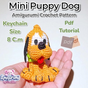Könnte beinhalten: Ein gehäkelter Mini-Welpen-Amigurumi-Schlüsselanhänger. Der Welpe ist orange, weiß, schwarz und rot, mit einem grünen Kragen. Der Text auf dem Bild lautet "Mini Puppy Dog Amigurumi Crochet Pattern" und "Keychain Size 8 cm".