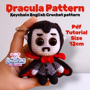 Puede incluir: Llavero de Drácula tejido a ganchillo, con capa negra, pajarita roja y chaleco gris. Mide 12 cm de alto. El texto en la imagen dice "Dracula Pattern" y "Keychain English Crochet pattern".