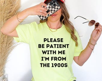 May include: A neon yellow t-shirt with the text "PLEASE BE PATIENT WITH ME I'M FROM THE 1900S" printed in black.