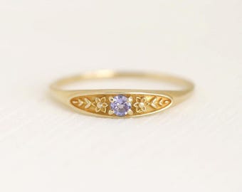 May include: A gold ring with a delicate floral design and a small purple gemstone in the center.