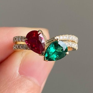 May include: A gold ring featuring a pear-shaped ruby and a pear-shaped green gemstone set in a band of diamonds.