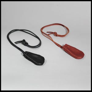 May include: Two leather pouches with cords, one black and one brown. The pouches are hanging from the cords.