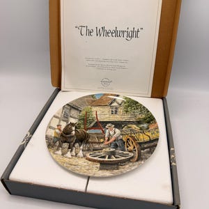 May include: Decorative plate titled "The Wheelwright" featuring a detailed rural scene with a man working on a wagon wheel, a horse, and a cart. The plate is in a box with a printed description.