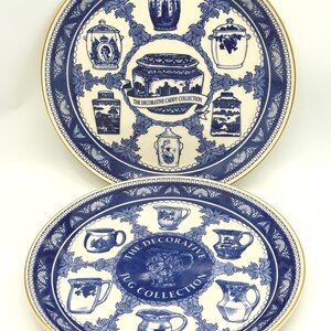 May include: Two decorative ceramic plates with blue and white patterns. The top plate is round and features the text "The Decorative Caddy Collection." The bottom plate is oval and features the text "The Decorative Jug Collection."