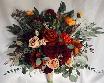 May include: A bouquet of burgundy, red, orange, and peach roses with greenery, including eucalyptus and sprigs of dried grasses.