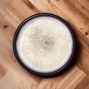 May include: A white candle with silver glitter in a black jar.