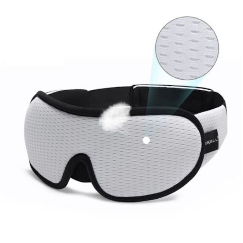 May include: White sleep mask with a black adjustable strap and a breathable mesh fabric. The mask has a small light sensor on the front.