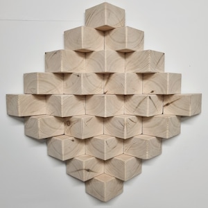 Puede incluir: Una pieza de arte de pared hecha de bloques de madera natural dispuestos en forma de diamante. Los bloques están apilados en un patrón escalonado, creando un diseño geométrico.