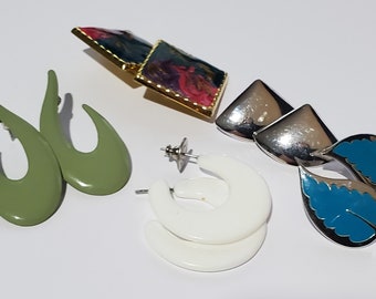 May include: Assortment of vintage earrings in various styles and colors.  The earrings include a pair of green oval-shaped earrings, a pair of white hoop earrings, and a pair of silver earrings with blue leaf accents.