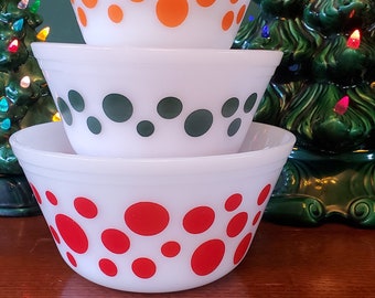 May include: Three white mixing bowls with different colored polka dots. The top bowl has orange dots, the middle bowl has green dots, and the bottom bowl has red dots.