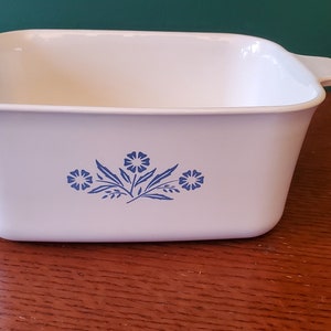 Puede incluir: Plato para hornear de cerámica blanca con diseño floral azul. El plato tiene dos asas a los lados.