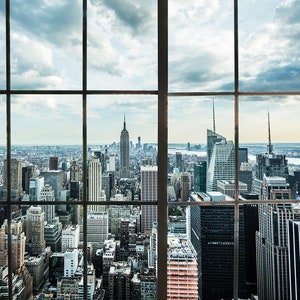 Puede incluir: Una vista del horizonte de la ciudad de Nueva York a través de una gran ventana con múltiples paneles. El Empire State Building es visible en la distancia.