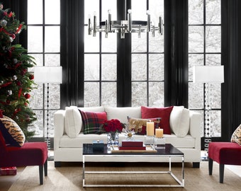 Könnte beinhalten: Ein weißes Sofa mit roten und karierten Kissen steht in einem Wohnzimmer mit einem Weihnachtsbaum, zwei roten Sesseln und einem Glas-Couchtisch.