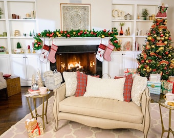 Könnte beinhalten: Ein Wohnzimmer, das für Weihnachten mit einem beleuchteten Kamin, einem geschmückten Weihnachtsbaum und einem Sofa mit rot-weiß karierten Kissen dekoriert ist.