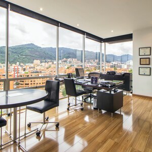 Peut inclure: Un espace de bureau moderne avec une grande fenêtre donnant sur un panorama urbain. Le bureau est doté d'un sol en bois, d'un grand bureau avec un ordinateur portable et d'une petite table avec des chaises.
