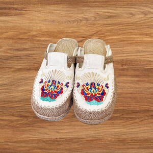 Close up of embroidered canvas mule shoes with breathable woven toe and flexible espadrille sole