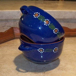 May include: Two blue ceramic soup bowls with white and brown floral designs. The bowls are stacked on top of each other.