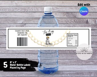 Könnte beinhalten: Fünf 8 x 2 Zoll große weiße Wasserflaschenetiketten mit schwarzem Text. Die Etiketten zeigen eine goldene Kette mit einem Baby, das eine Krone trägt, und den Text "The Big One" und "Gia's 1st Birthday". Die Etiketten enthalten auch einen Nährwertangaben-Abschnitt mit dem Text "Friends, Fun, Joy, Memories, Good Times".